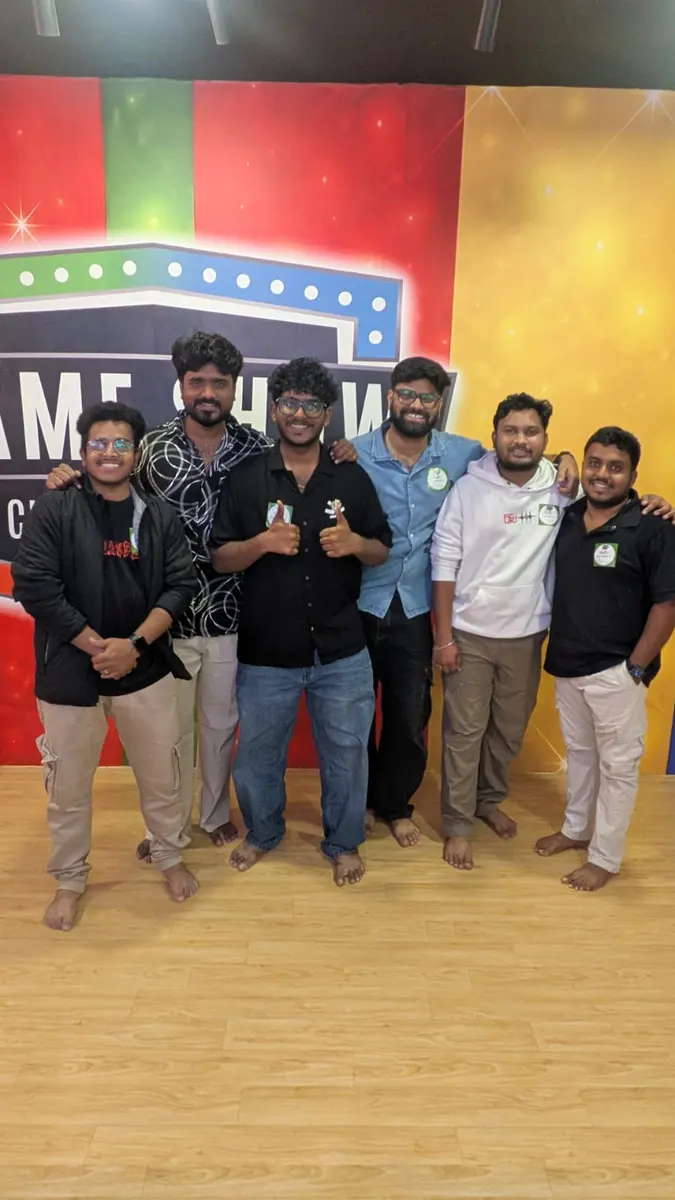 Friends giving thumbs up in front of the logo wall