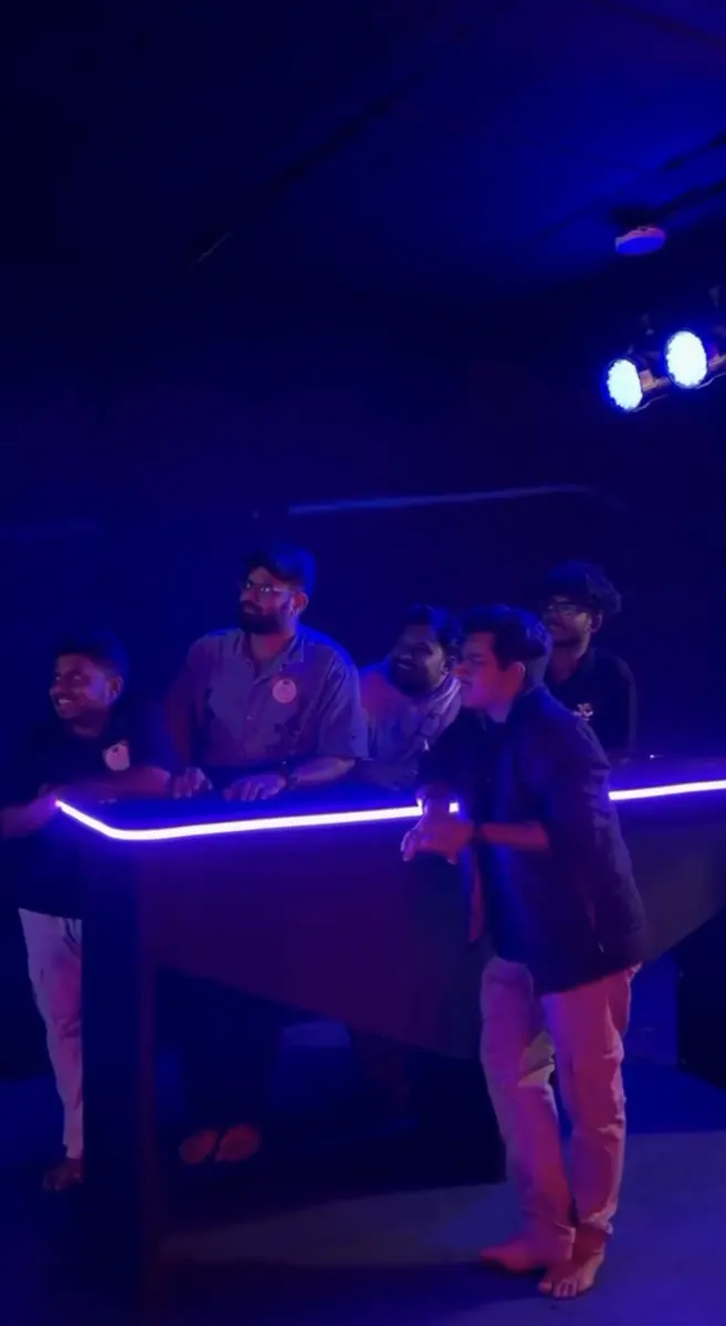 A team leaning over the glowing buzzer desk