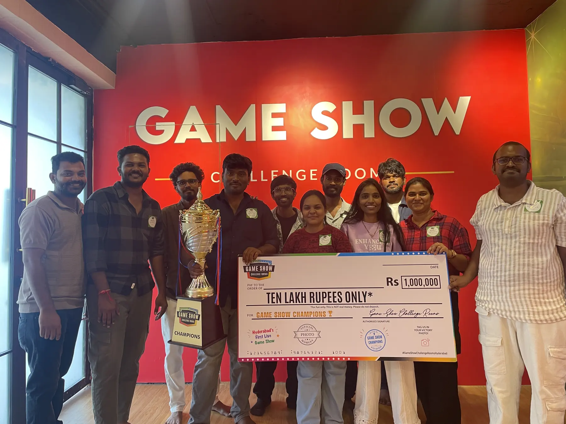 A winning team holding the champions trophy and the giant cheque