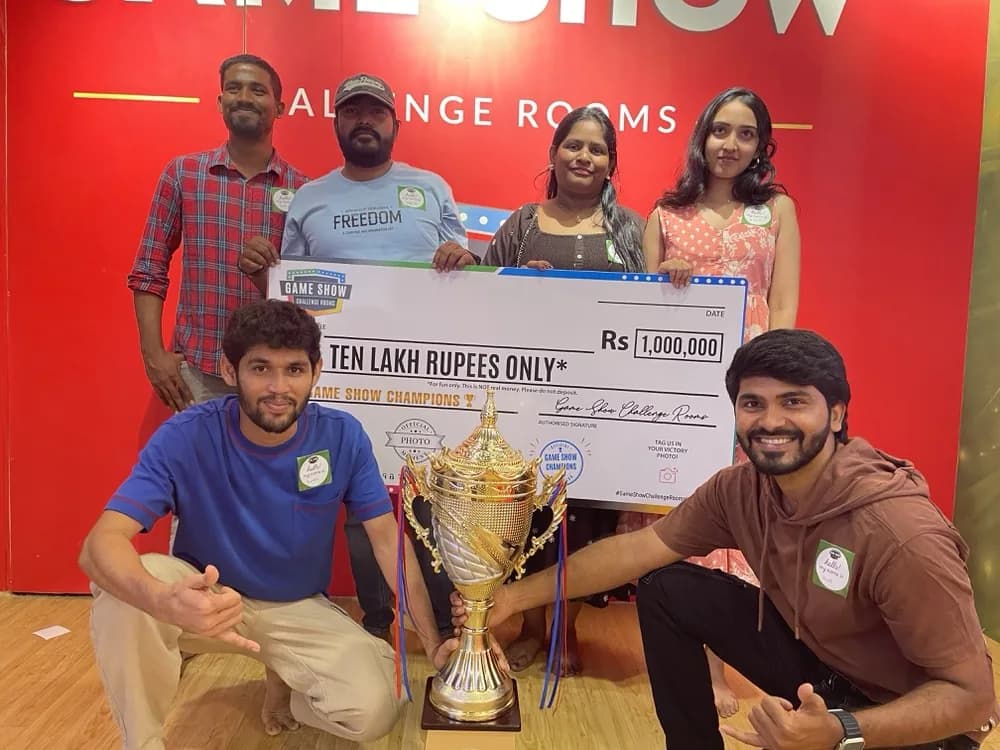 Winners posing with the trophy and cheque by the red wall